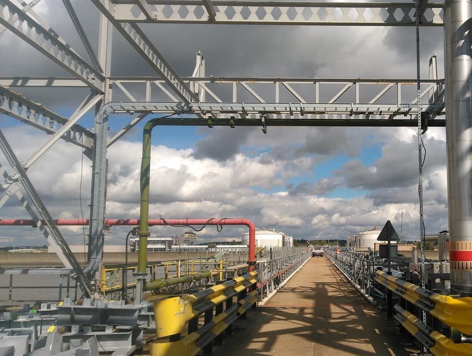 The jetty gantry and pipe-rack the new cables were routed along, with storage tanks across the estuary
