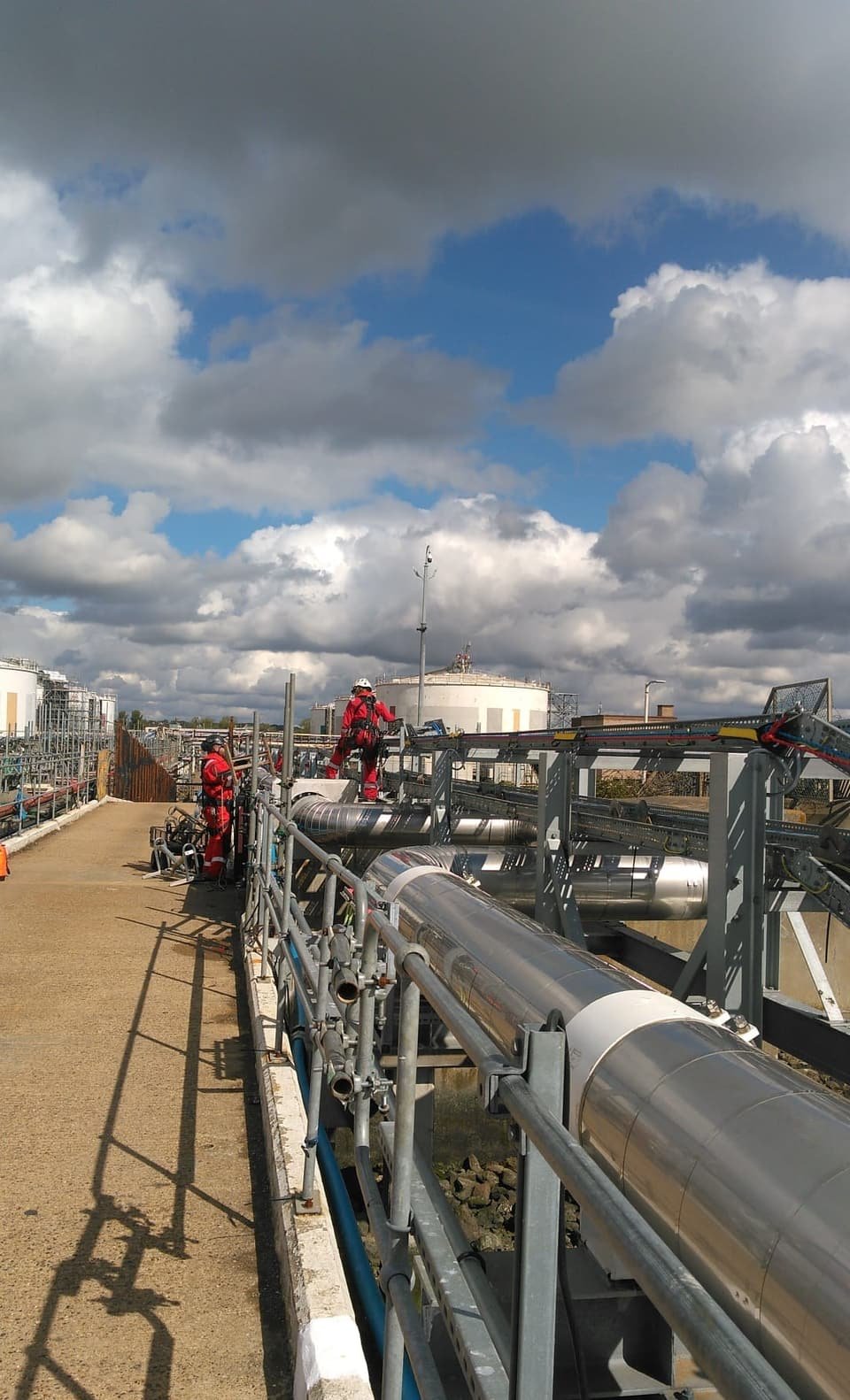 Technicians working along a pipe-rack walkway at a gas terminal