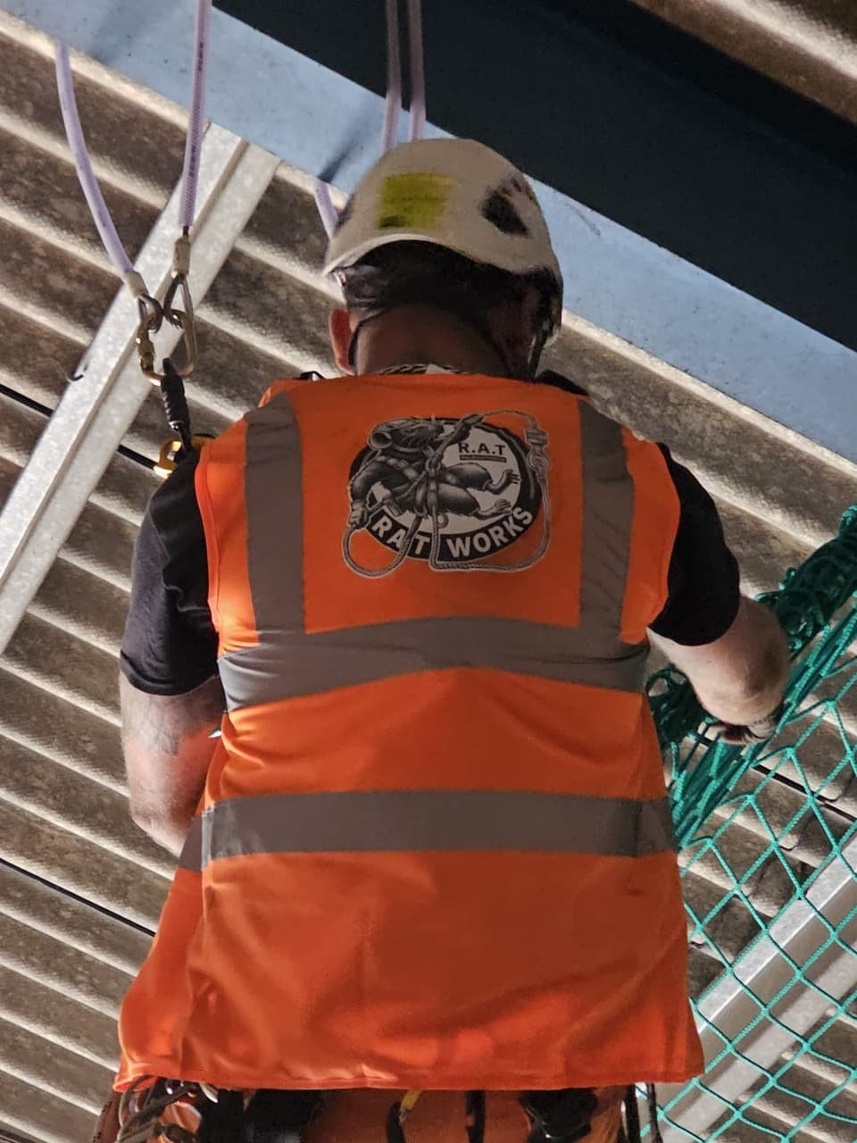 Technician working inside a safety net under a roof structure
