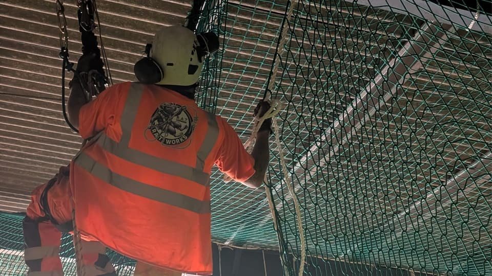 Safety netting install under a roof, technician on rope