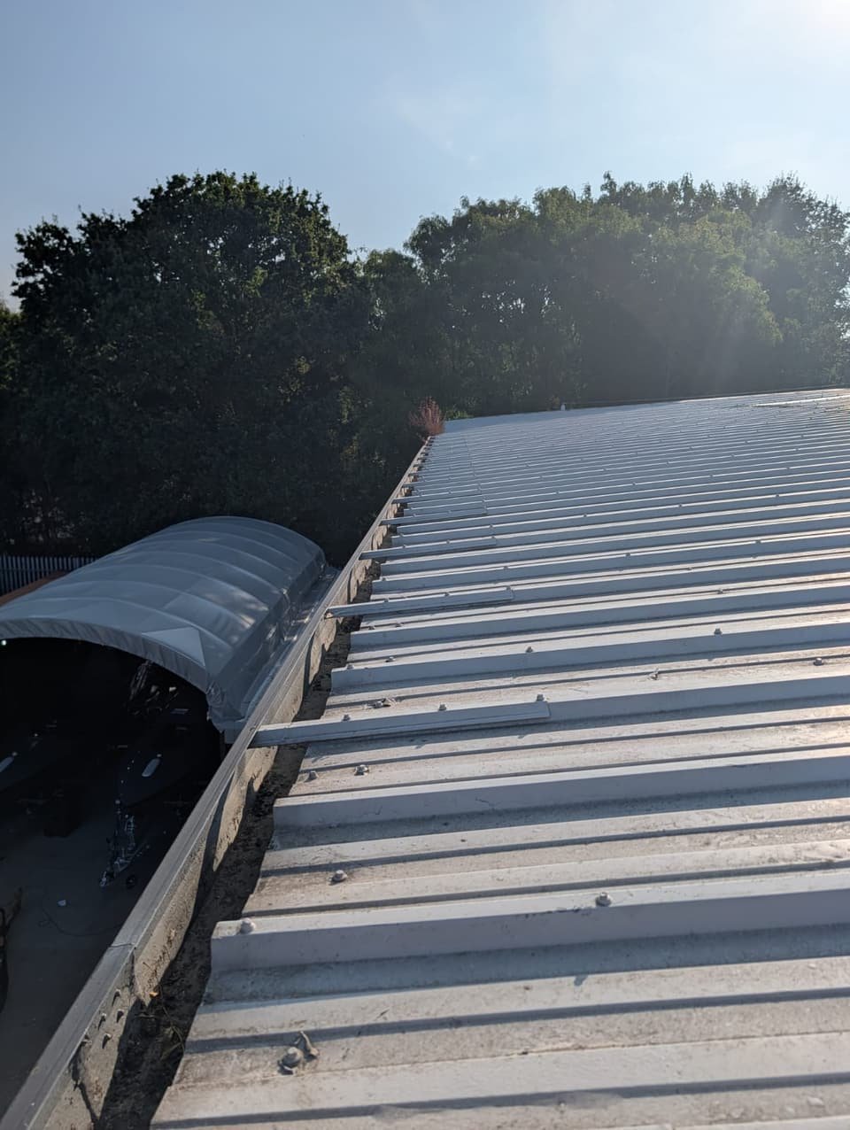 Boundary gutter after clearance, running clean along the edge of the warehouse roof