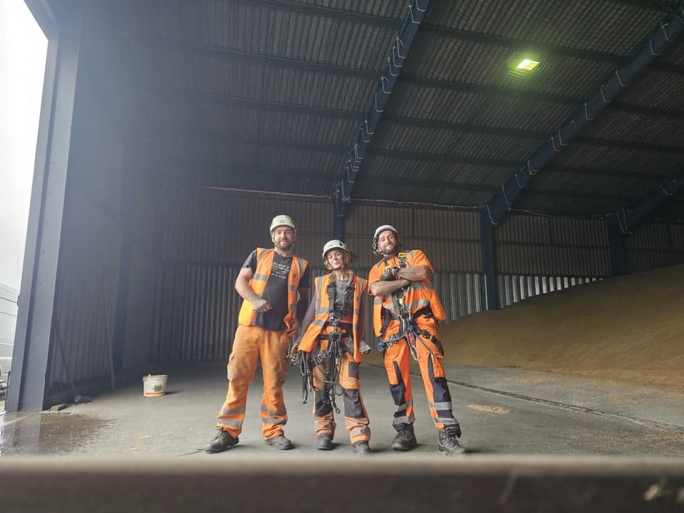 Three RAT Work technicians in full rope access kit inside a barn